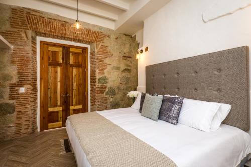 1 dormitorio con cama y pared de ladrillo en Hotel Tabáa Oaxaca en Oaxaca de Juárez