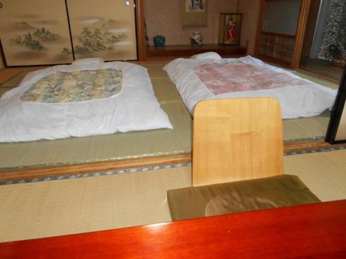 two beds sitting on the floor in a room at ゲストハウスよろずや in Nahari