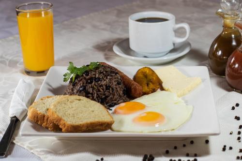 einen Teller mit Eiern und Brot und eine Tasse Kaffee in der Unterkunft Hotel Mar de Luz in Jacó
