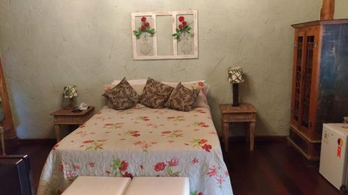 a bedroom with a bed and two night stands at Pousada Quinta dos Pássaros Itaipava in Itaipava