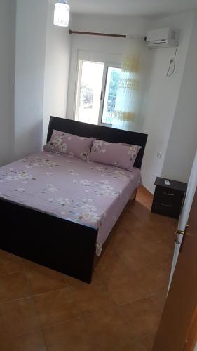 um quarto com uma cama com lençóis roxos e uma janela em gzim's apartment em Durrës