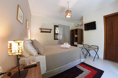 a bedroom with a bed and a table and a lamp at Club do Balanço Pousada e Restaurante in Morro de São Paulo