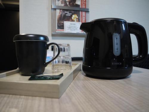 a black coffee maker and a cup on a table at Hotel Route-Inn Osaka Kishiwada -Higashikishiwada Ekimae Kansai Airport- in Kishiwada