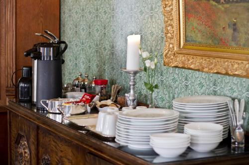 a table with a bunch of plates and a candle at Hotel Kong Carl - Unike Hoteller in Sandefjord