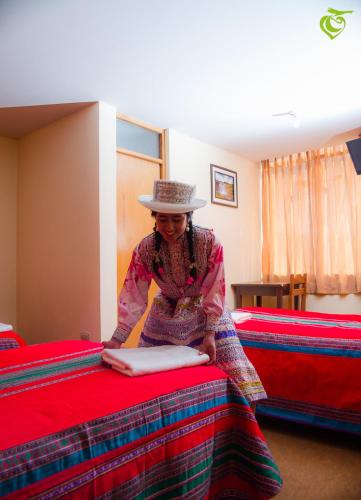 a woman in a hat is making a bed at Sonqo Killa del Colca in Chivay