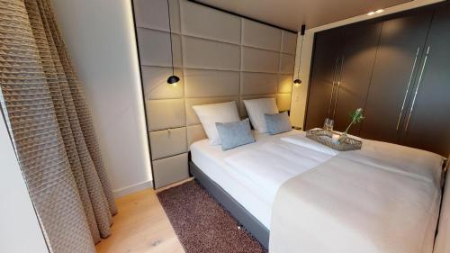 una camera da letto con un grande letto bianco con cuscini blu di White Pearl Apartment 2.08 a Timmendorfer Strand