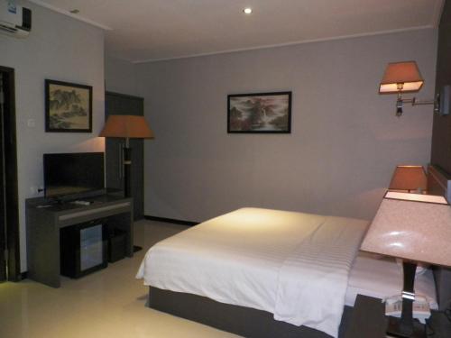 a bedroom with a bed and a flat screen tv at Hotel Victory Bandung in Bandung