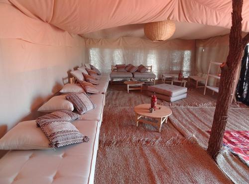 a room with a bunch of couches in a tent at Maroc Sahara Luxury Camp & Tours in Foum Zguid