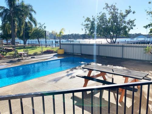 a swimming pool with a picnic table next to a fence at Mariners on the Waterfront in Batemans Bay