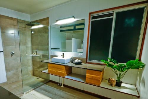 a bathroom with a sink and a shower with a mirror at The Summit 1770 in Agnes Water