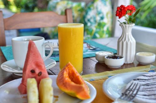 uma mesa com um prato de fruta e um copo de sumo de laranja em Club do Balanço Pousada e Restaurante em Morro de São Paulo