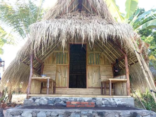 a small hut with a thatch roof and a door at Uma Nirmala Aling-Aling in Singaraja