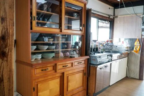 a kitchen with a wooden cabinet with dishes in it at guest house komoriya in Matsumoto