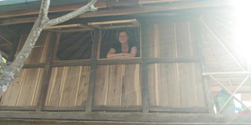 a woman looking out of a window in a wooden building at ESA di Kubu Homestay in Singaraja