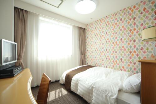 a hotel room with a bed and a television at Hotel Wing International Tomakomai in Tomakomai