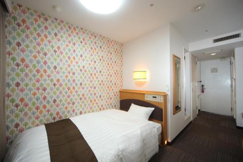 a bedroom with a white bed and a floral wallpaper at Hotel Wing International Tomakomai in Tomakomai