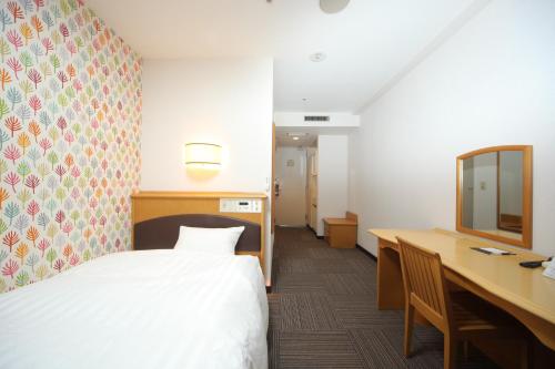 a bedroom with a bed and a desk and a mirror at Hotel Wing International Tomakomai in Tomakomai