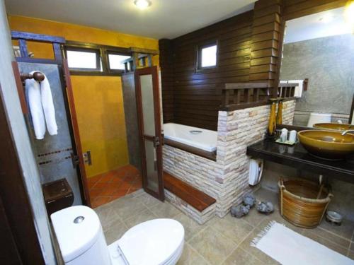 a bathroom with a tub and a toilet and a sink at Phunacome Resort in Dan Sai