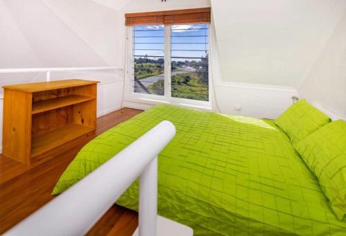 a green bed in a room with a window at Kendall Beach Apartments 5 - Belongil Beach in Byron Bay