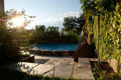a swimming pool in a yard with the sun shining at Hotel Rotwand in Laives