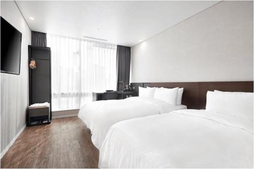 a hotel room with two beds and a television at Arban City Hotel in Busan