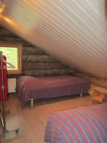 a attic room with two beds and a window at Rukakaiku Cottages in Ruka