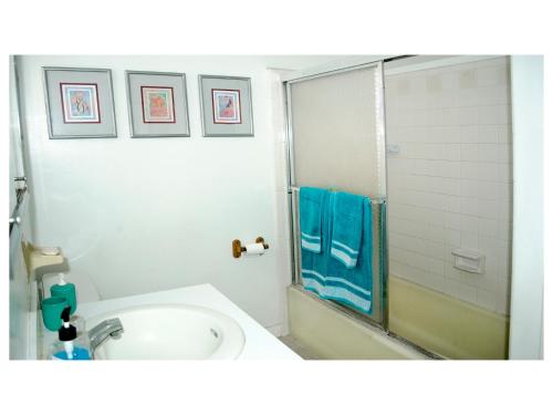 ein weißes Bad mit einer Dusche und einem Waschbecken in der Unterkunft Beauport One-Bedroom Apartment in Freeport