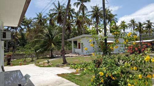 a house with a garden with yellow flowers and palm trees at Kathleens Vacation Place in Moalboal