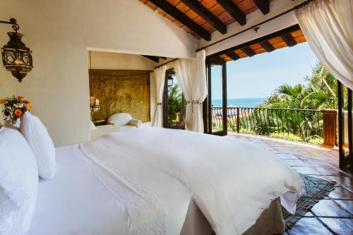 a bedroom with a large white bed and a balcony at Hacienda San Angel in Puerto Vallarta