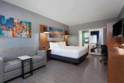 a hotel room with a bed and a couch at La Quinta by Wyndham Ft. Myers - Sanibel Gateway in Fort Myers