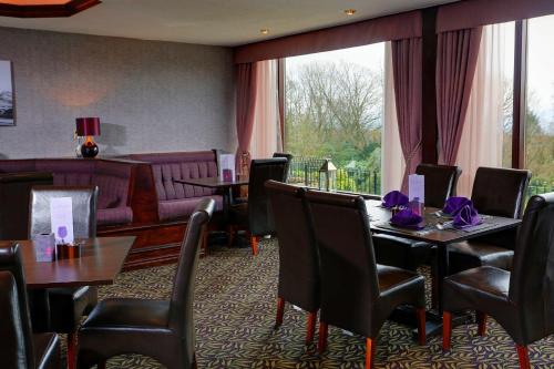 a dining room with tables and chairs and a couch at Burnley West Higher Trapp Hotel in Padiham