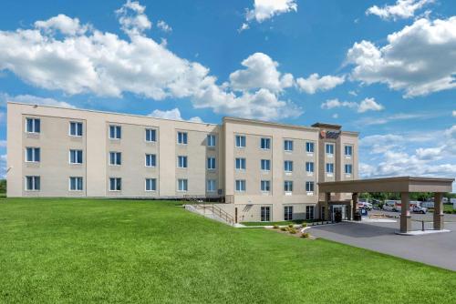 a large white building with a green lawn in front of it at Comfort Inn & Suites in Napanee