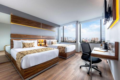 a hotel room with two beds and a desk with a computer at Sleep Inn Ciudad de Mexico Cuajimalpa in Mexico City