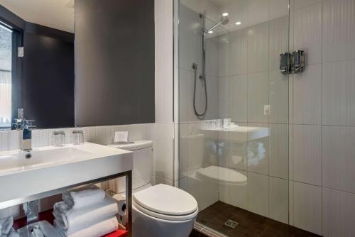 a bathroom with a shower and a toilet and a sink at Hotel Quartier, Ascend Hotel Collection in Quebec City