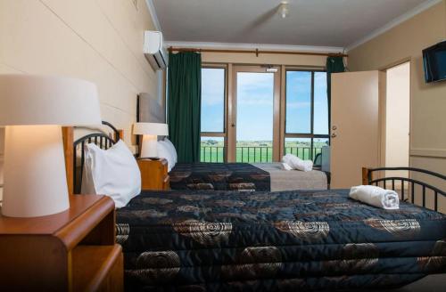 a hotel room with two beds and a window at Tailem Bend Riverside Hotel in Tailem Bend