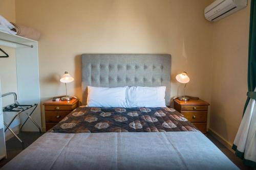a bedroom with a large bed with two night stands at Tailem Bend Riverside Hotel in Tailem Bend
