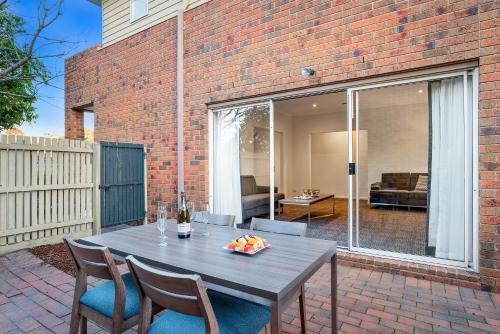 a wooden table and chairs on a patio at Quest Brighton on the Bay in Melbourne