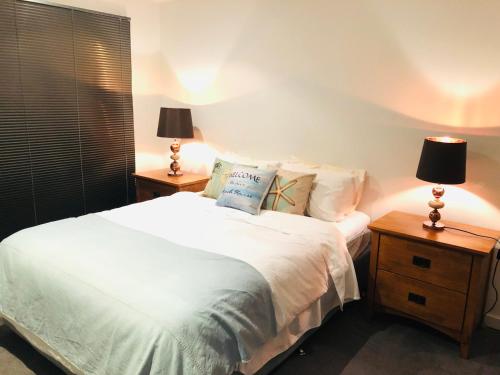 a bedroom with a white bed with two lamps on tables at Gorgeous 2 Bedroom Townhouse - Free Parking - Free WIFI in Torquay