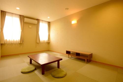 a room with a table and a bench and a window at Hotel Teiregikan in Tobe