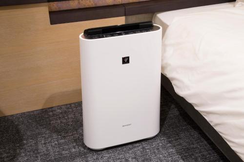 a white refrigerator sitting next to a bed at Shizutetsu Hotel Prezio Kyoto Karasumaoike in Kyoto