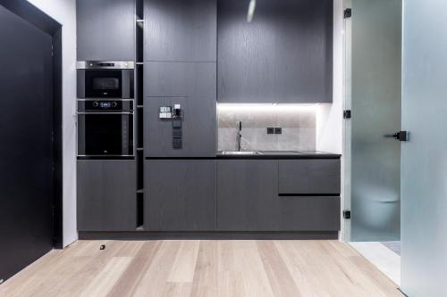 a kitchen with black cabinets and a sink at The Duke Boutique Suites in Athens