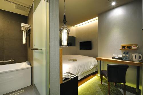 a room with a bed and a desk and a bathroom at Forward Suites II in Taipei