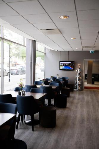 a restaurant with tables and chairs and a flat screen tv at City Central Hotel Örebro by First Hotels in Örebro