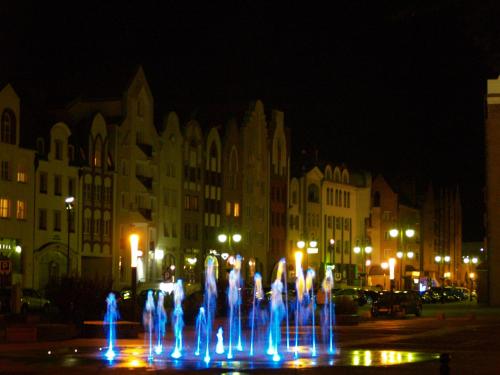 a water fountain in the middle of a city at night at Apartament Elbląg Centrum in Elblag