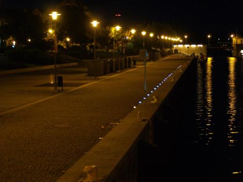 a street at night with lights on the water at Apartament Elbląg Centrum in Elblag