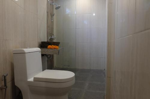 a white bathroom with a toilet and a shower at Dugul Hidden in Ubud