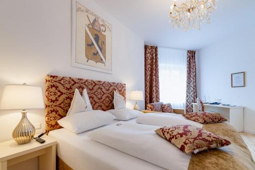 a bedroom with two white beds and a chandelier at Boutique Hotel Goldenes Lamm Villach in Villach