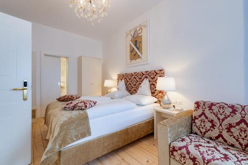a bedroom with a large bed and a chair at Boutique Hotel Goldenes Lamm Villach in Villach