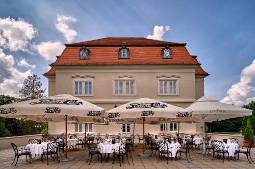 a group of tables and umbrellas in front of a building at La Contessa Castle Hotel in Szilvásvárad