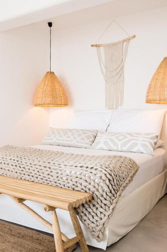 a white bedroom with a bed with a bench at San Michele in Procida